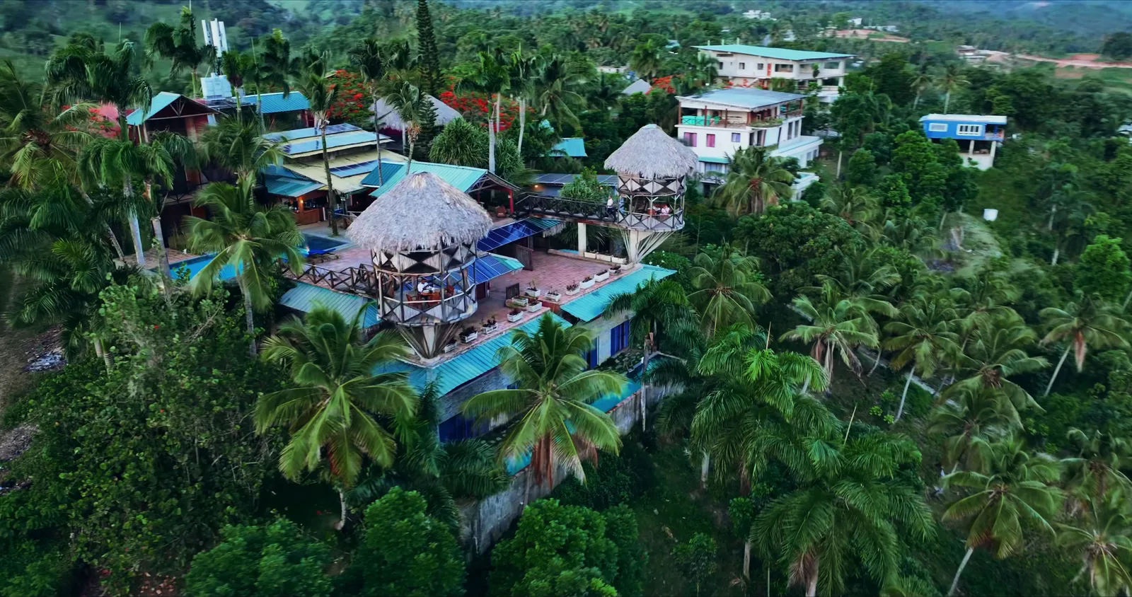 Construções do hotel com telhados coloridos entre palmeiras e árvores tropicais