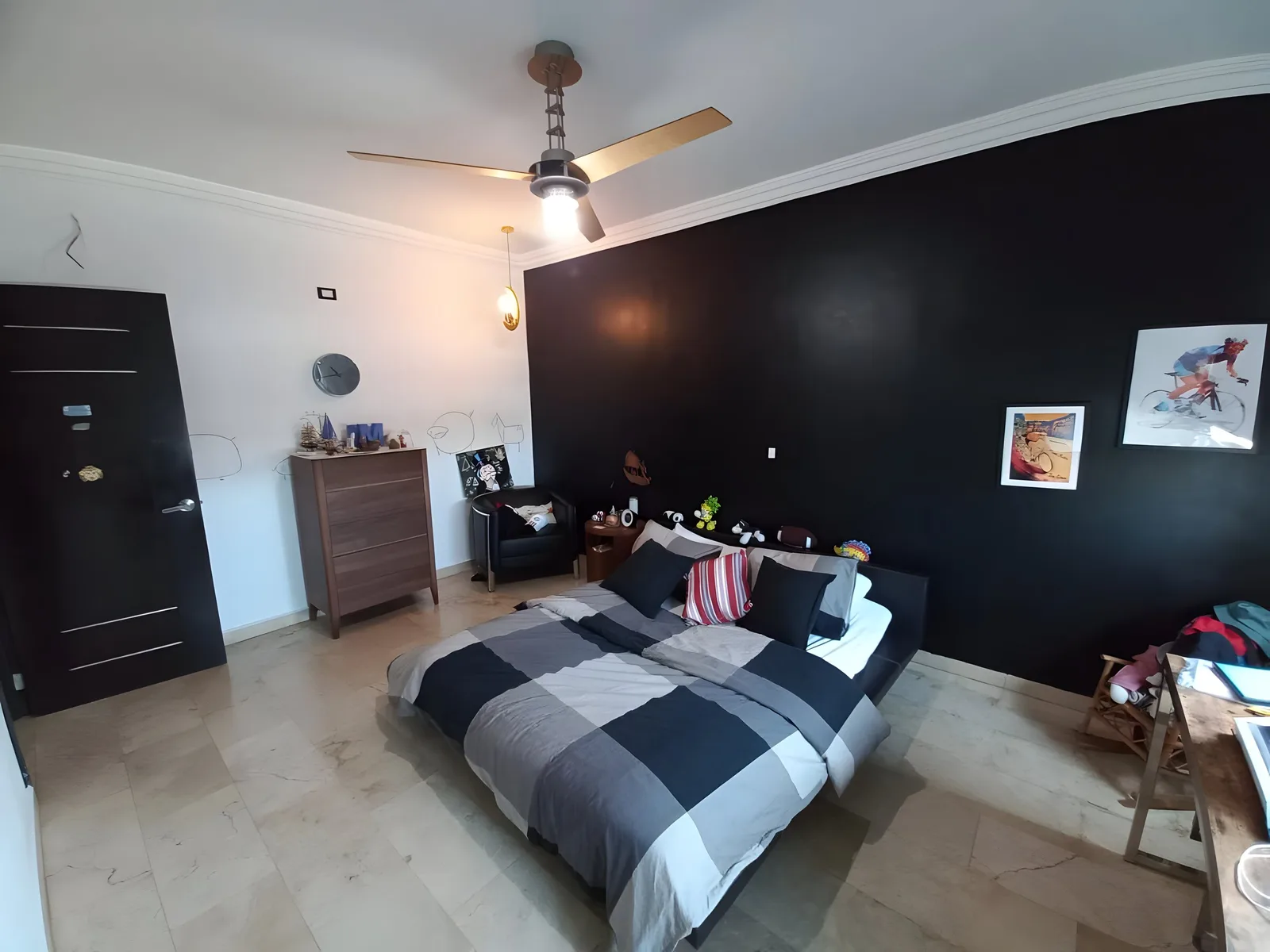 Bedroom with a dark feature wall, a ceiling fan, a double bed and a desk