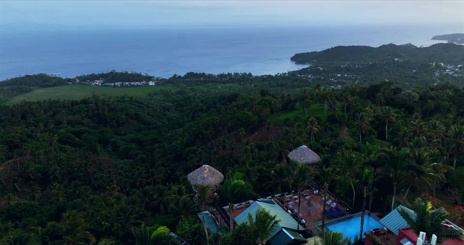 Telhados do hotel no meio da mata, com a baía de Samaná ao fundo
