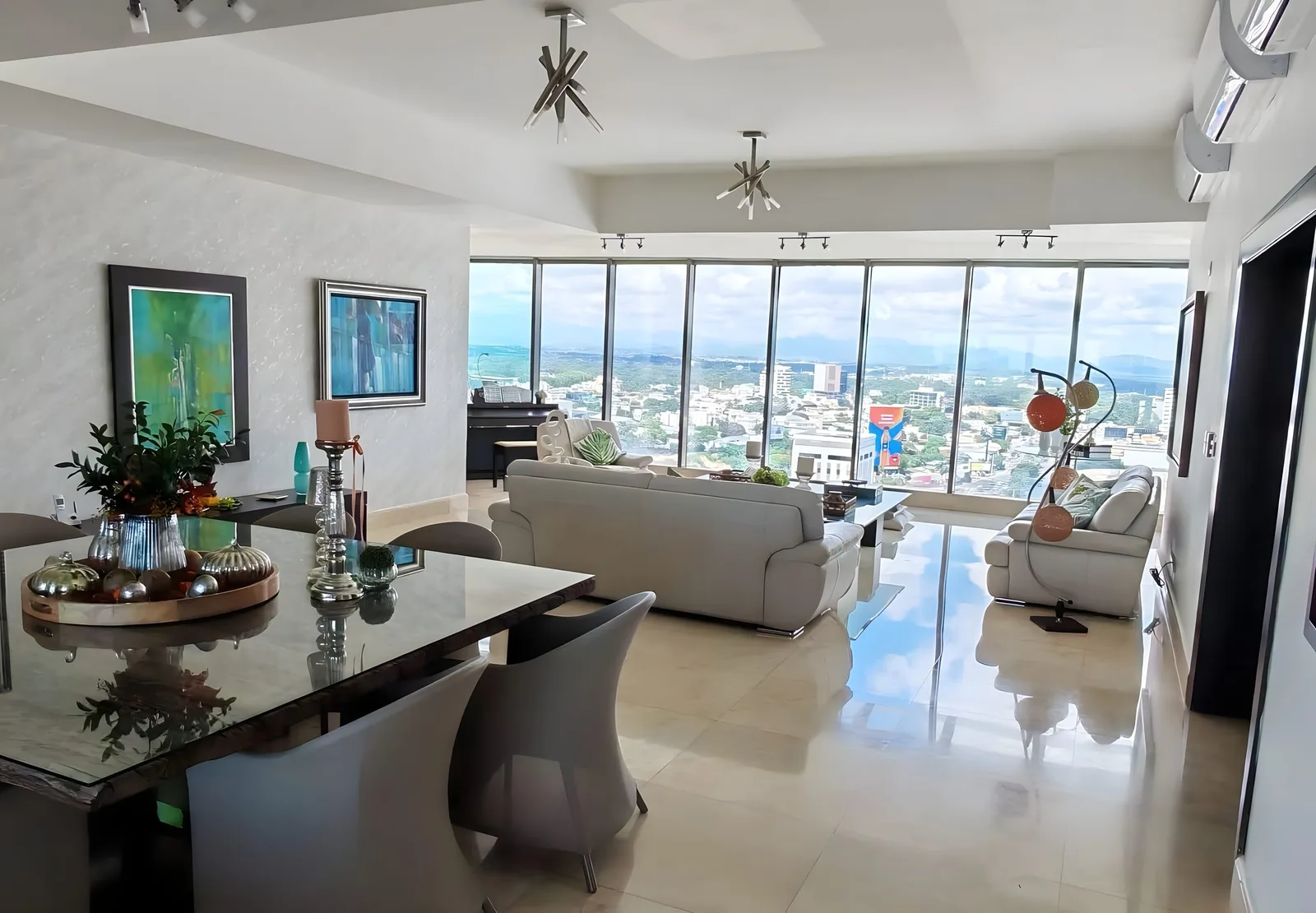 Dining table and living area in front of a wall of windows over the city