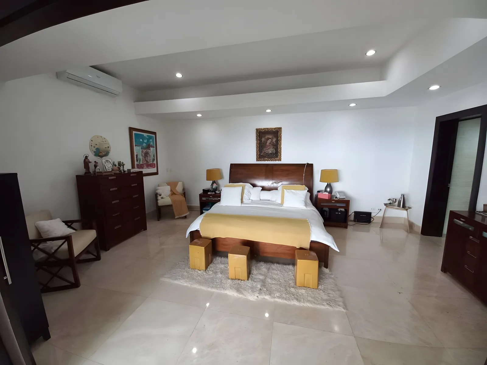 Bedroom with a large bed, wooden chests of drawers and an armchair
