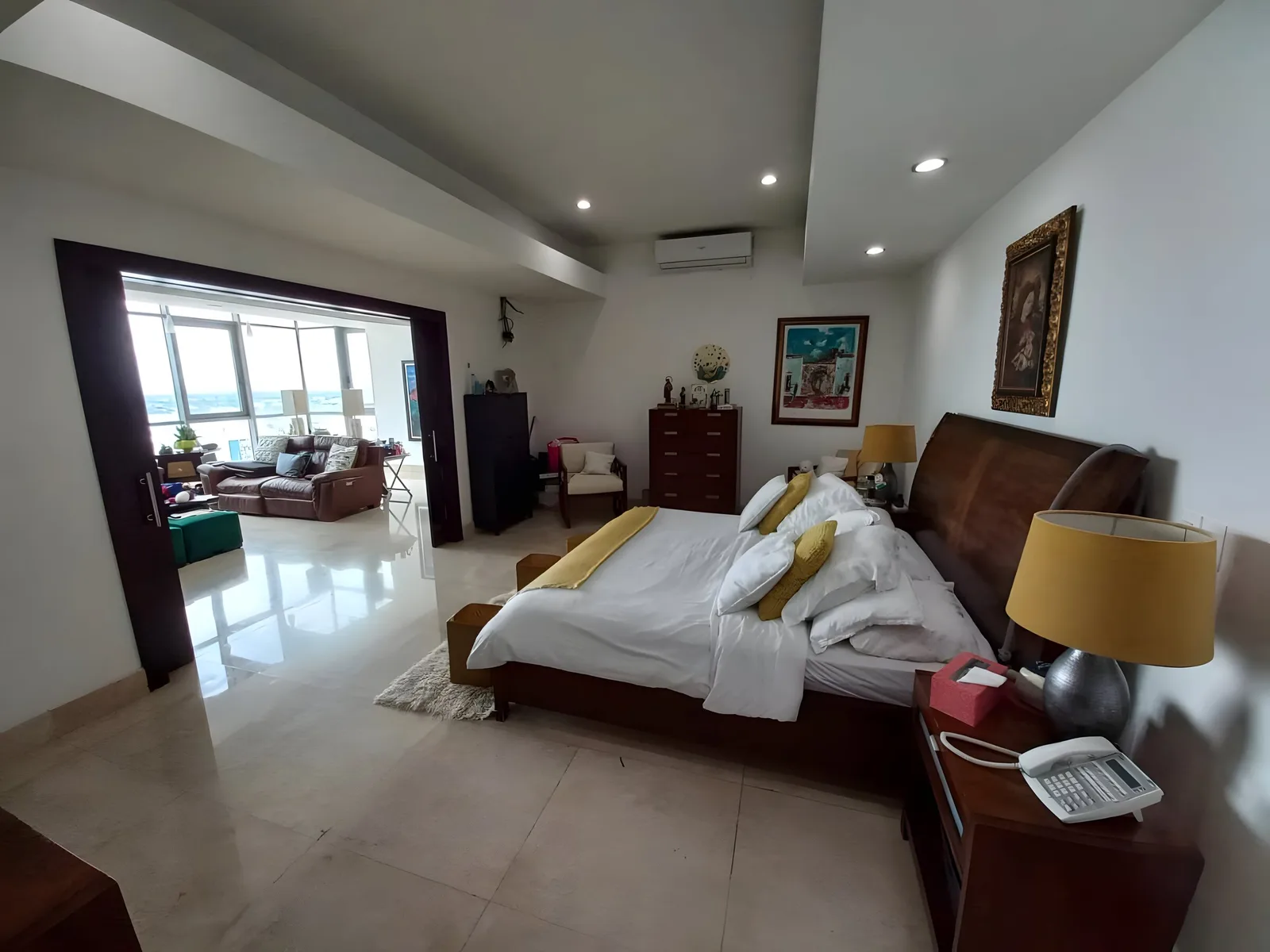 Main bedroom with a wooden bed and a sitting area by the windows